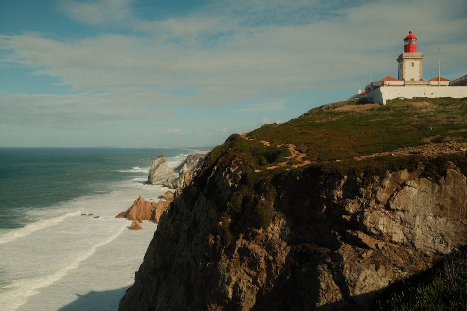 Dramatic coastal cliffs and lighthouse at Cabo da Roca in Colares, Portugal, during daytime.