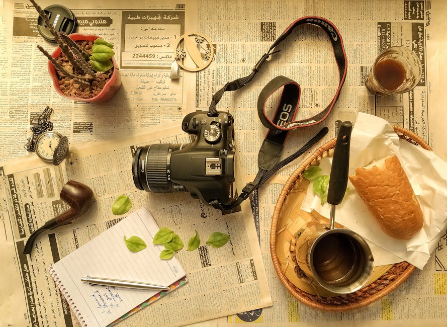 Flat lay with camera, bread, coffee, notebook, and vintage items on newspapers.